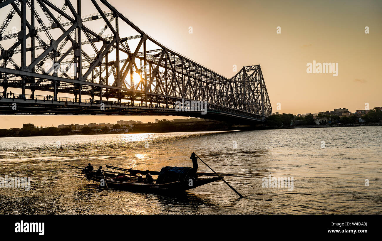 Silhouette of Howrah Bridge at the time of Sunrise.  Howrah Bridge is a bridge with a suspended span over the Hooghly River in West Bengal. Stock Photo