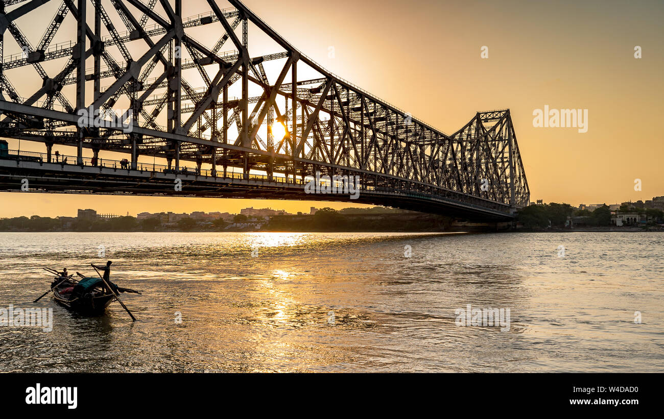 Silhouette of Howrah Bridge at the time of Sunrise.  Howrah Bridge is a bridge with a suspended span over the Hooghly River in West Bengal. Stock Photo