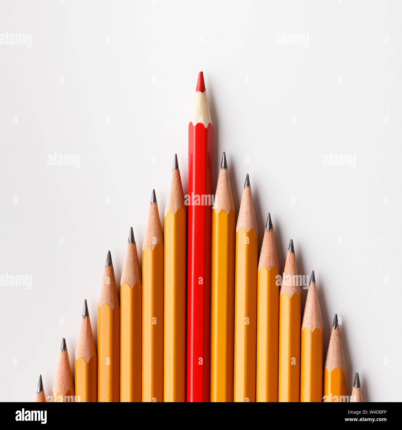 One red pencil leading similars crowd on white background Stock Photo