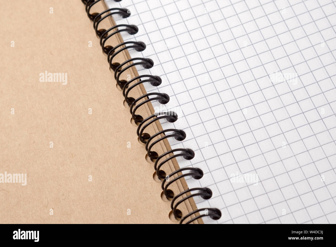 Notebook with checkered sheets on a wooden table. Close-up. Stock Photo
