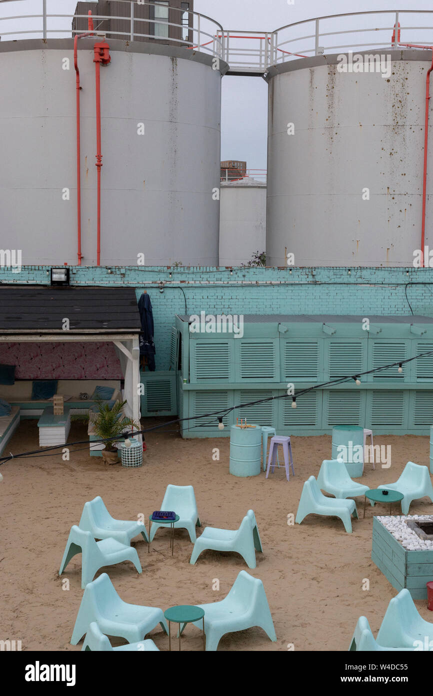View of Fulham Beach bar area in front of industrial tanks. Stock Photo