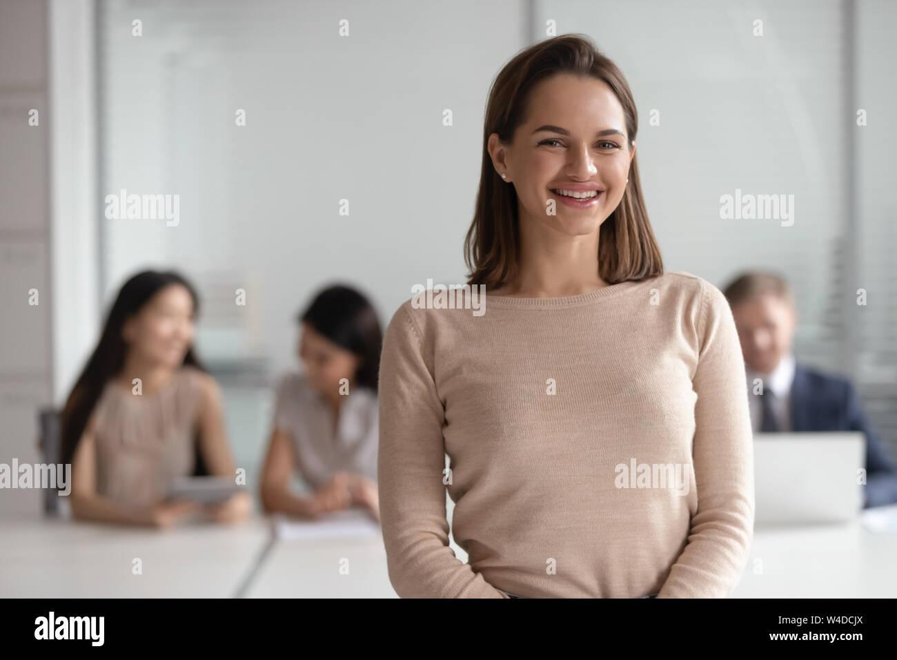 Cheerful young female leader looking at camera in corporate office Stock Photo