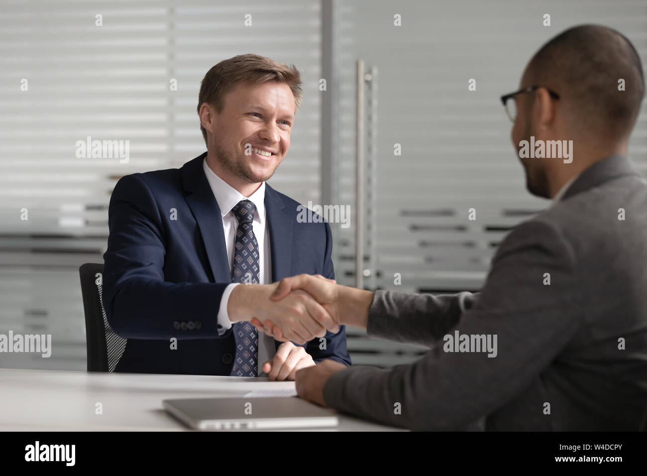 Happy diverse businessmen shake hands make business agreement at meeting Stock Photo