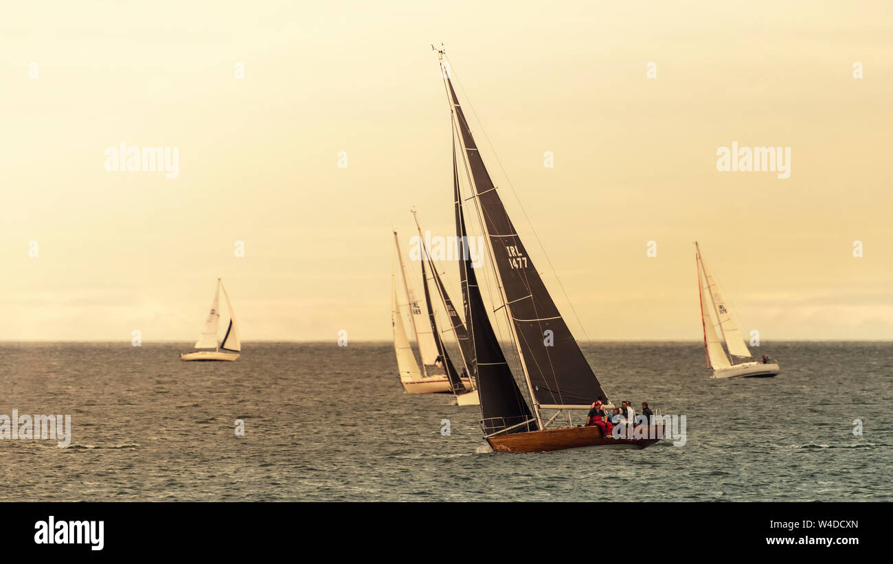 Sailing together. Group of sailboats sails in line during sail club regatta near Greystones