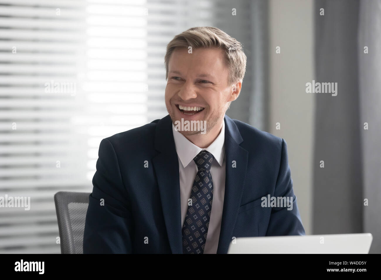 Happy cheerful businessman in suit laughing sit at work desk Stock Photo