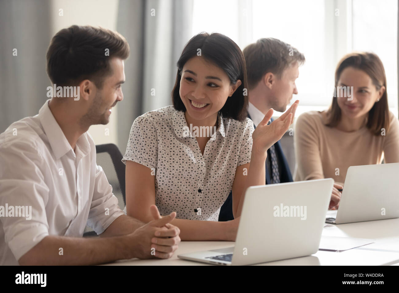 Happy diverse employees talking laughing working together with coworkers laptops Stock Photo