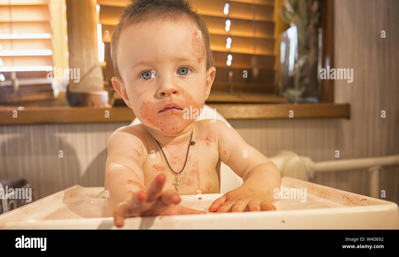 Young boy smeared in strawberry juice and asks for supplements Stock Photo