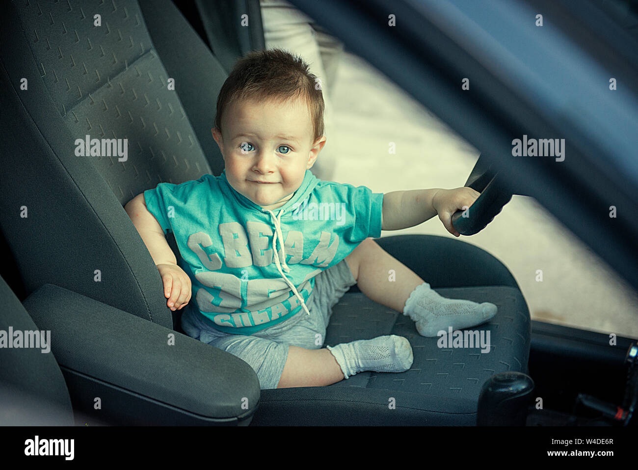 one and a half year old child sits behind the wheel of a car Stock