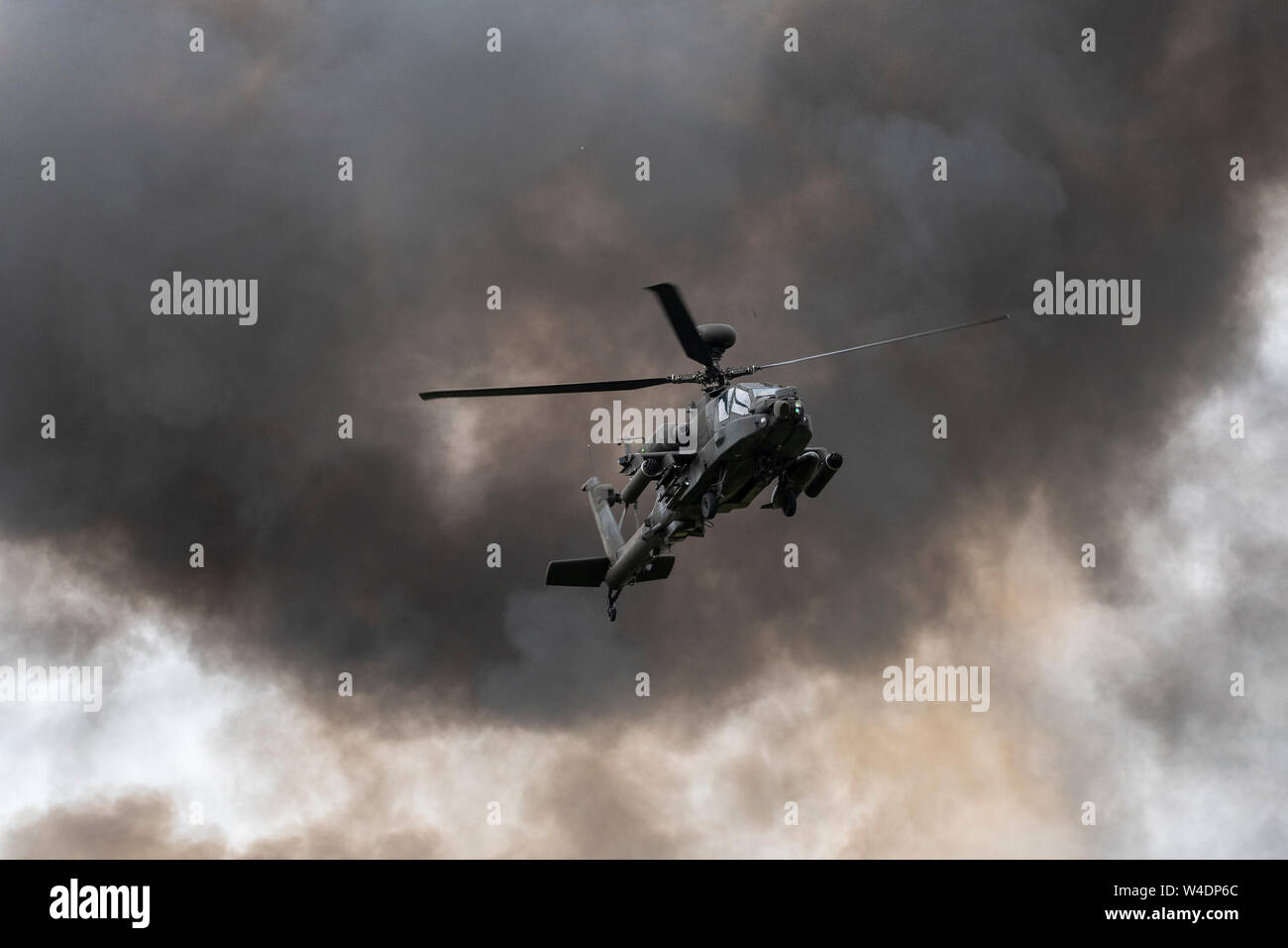 Agusta Westland Apache AH1 amongst  the ground smoke from the tactical demonstration on the last day of RIAT's annual show which is  regarded as the world's largest military airshow with participating aircraft flying in from all over the globe with over the globe .  20 nations took part and over  200,000 people were  expected to attend over the 3 days This years event celebrates 70 years of NATO. Stock Photo