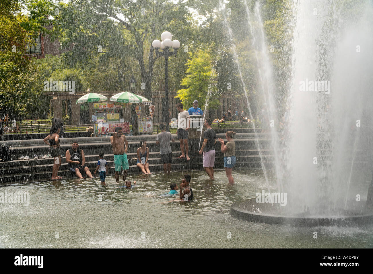 New Yorkers and visitors frolic by the fountain in Washington Square Park in Greenwich Village in New York on Saturday, July 20, 2019. An excessive heat warning is in effect in New York from noon Friday until 8PM Sunday as the oppressive combination of heat and humidity will make it feel like 105 degrees F. (© Richard B. Levine) Stock Photo