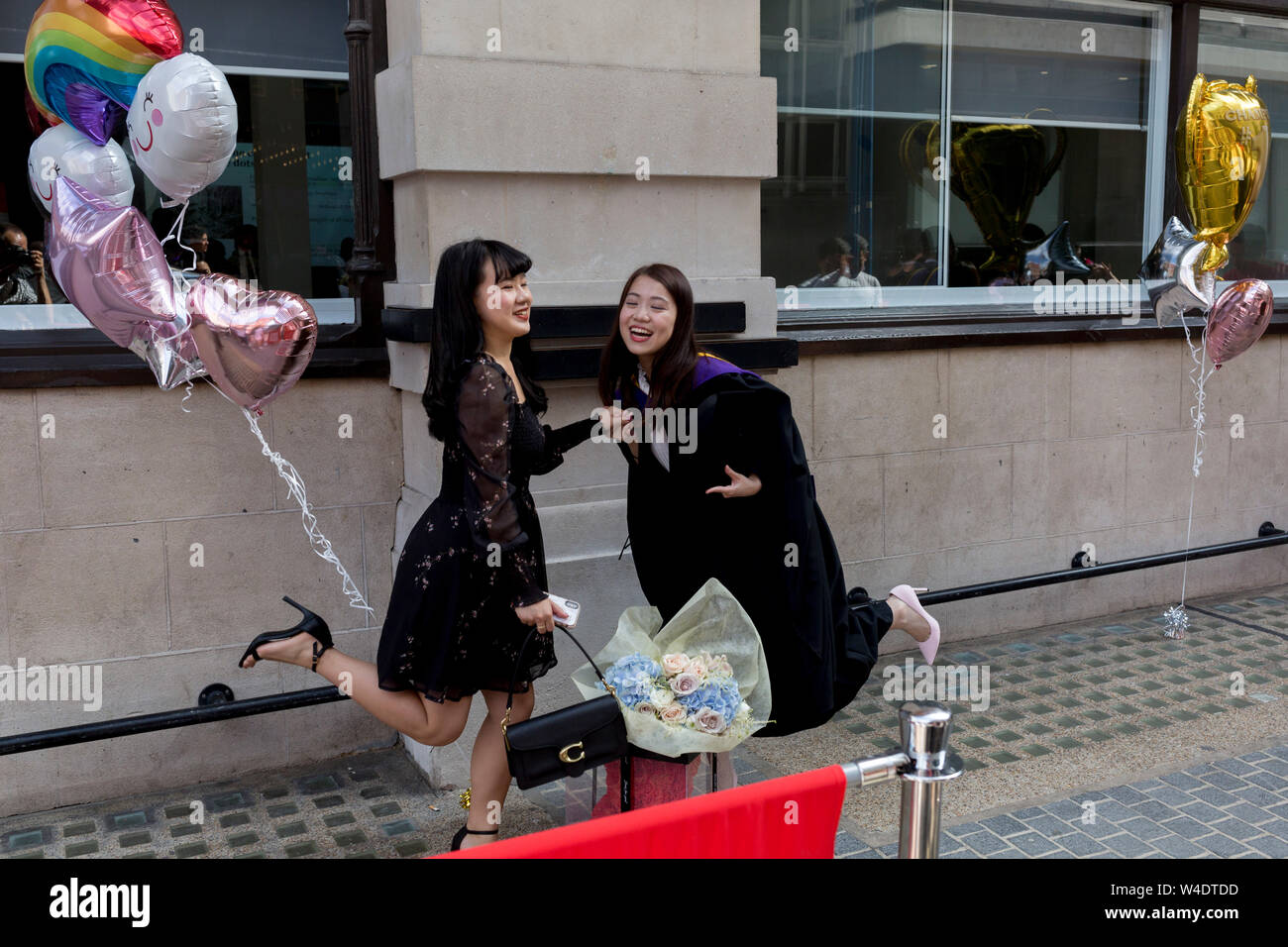 Friends and family of Hillary Chung (right), a 21 year-old Law graduate from Hong Kong, celebrate her graduation with a 2:1 degree outside the London School of Economics (LSE) after her graduation ceremony, on 22nd July 2019, in London, England. Stock Photo