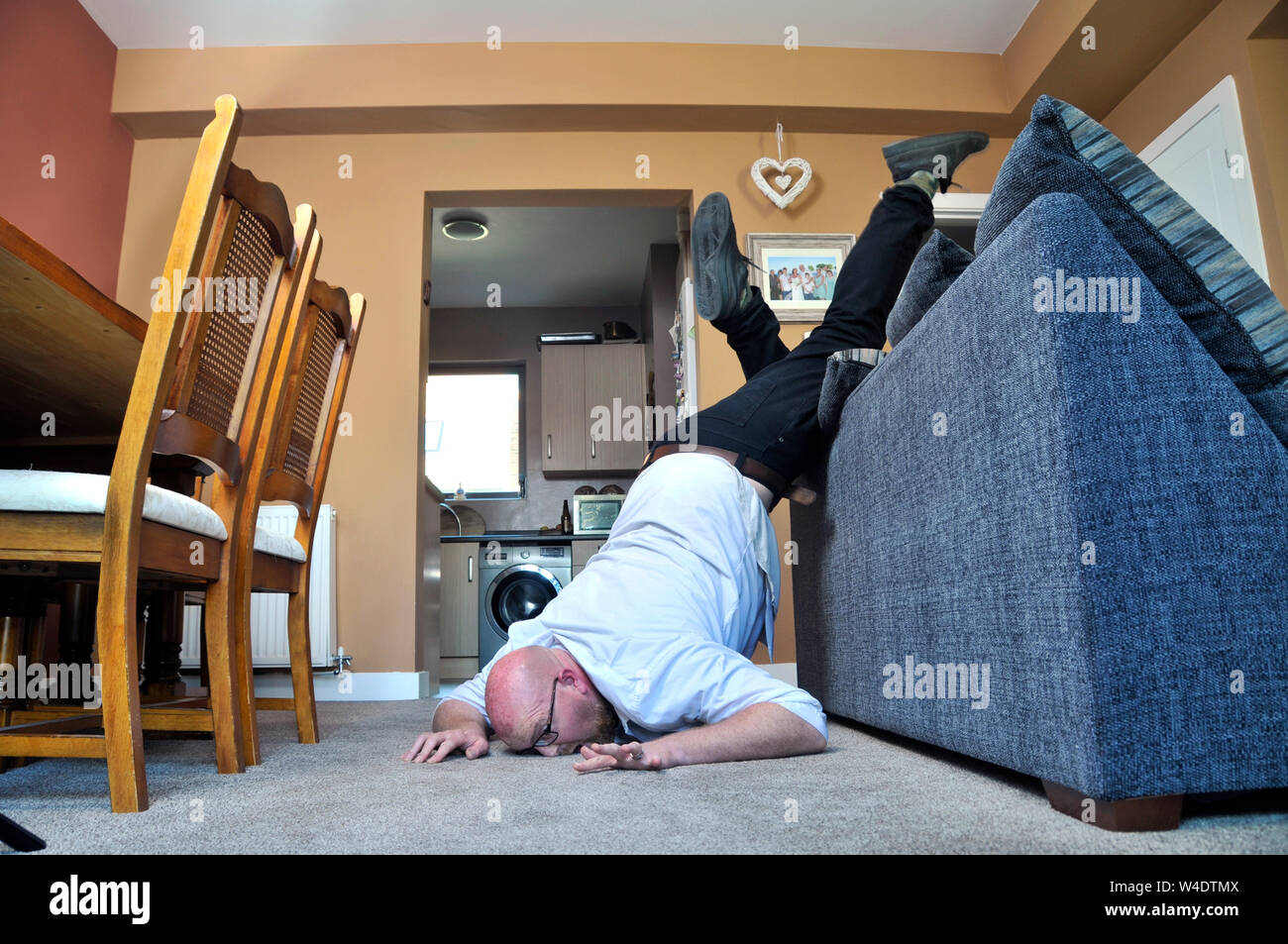 man falling over sofa Stock Photo