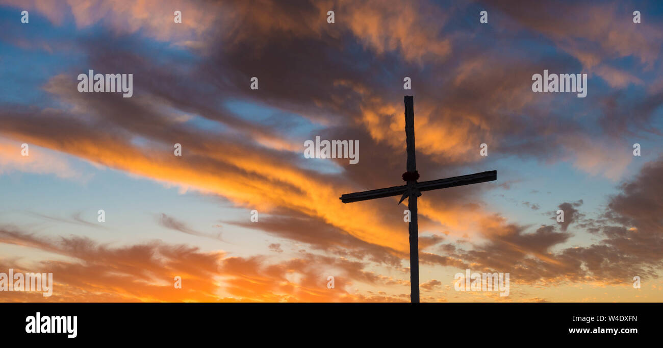 Cross on mountain summit at sunrise. Stock Photo
