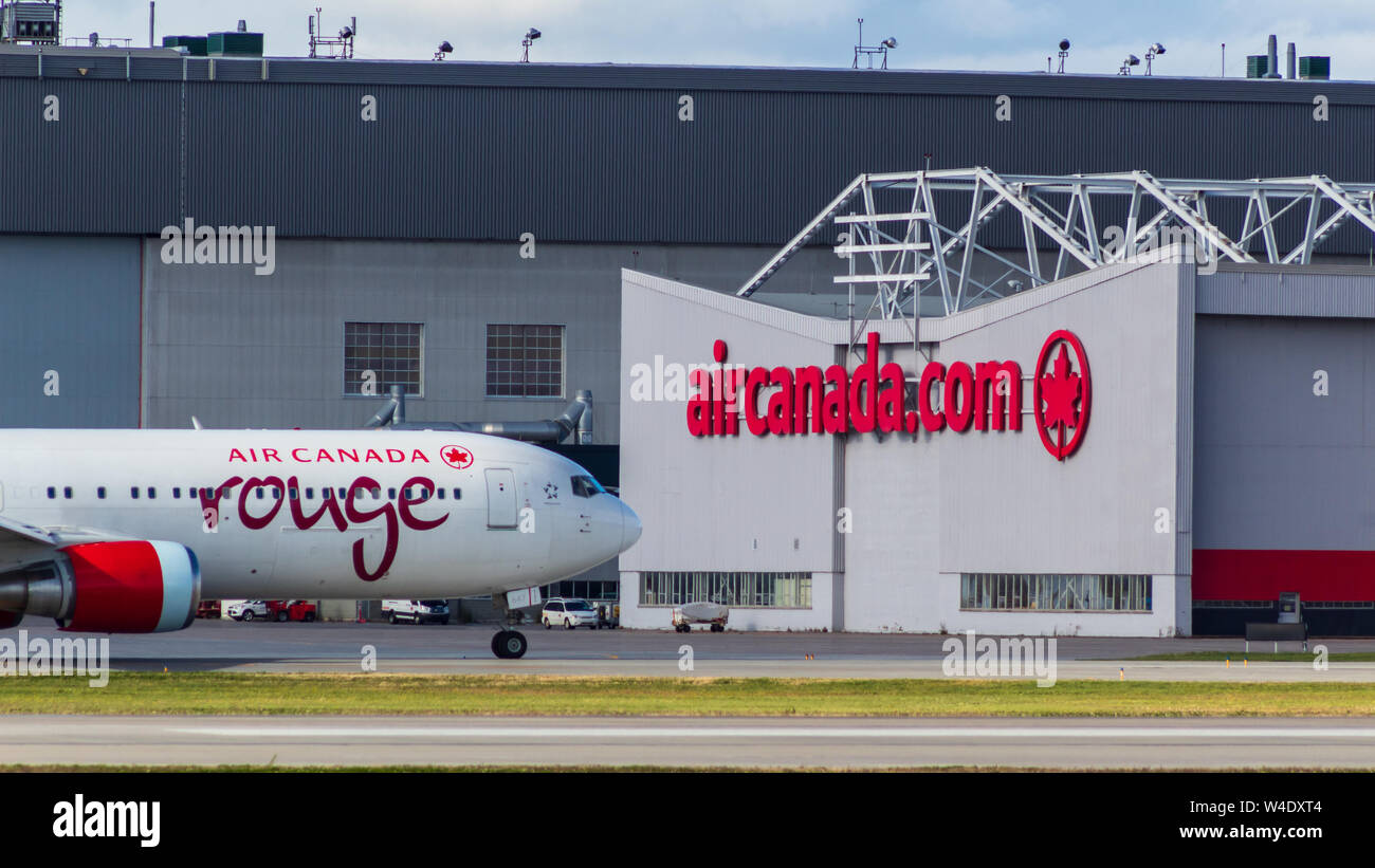 Air Canada Rouge Boeing 767 seen in-front of Air Canada's main hanger at Montreal-Pierre Elliott Trudeau International Airport. Stock Photo