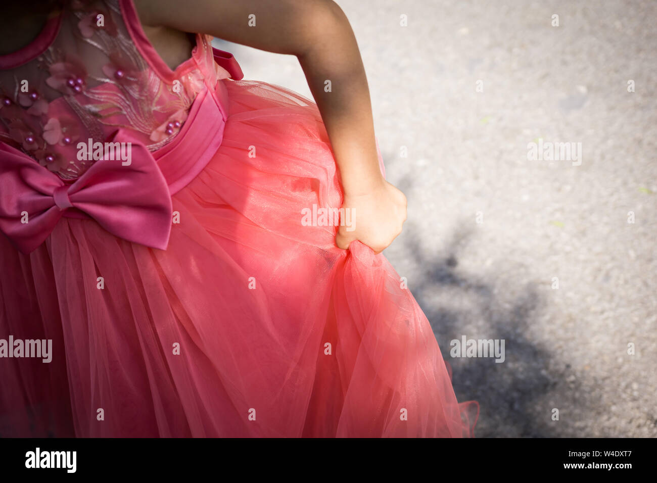 Close-up of part of a little girl with a coral-dress princess dress. Shallow depth of focus. Stock Photo