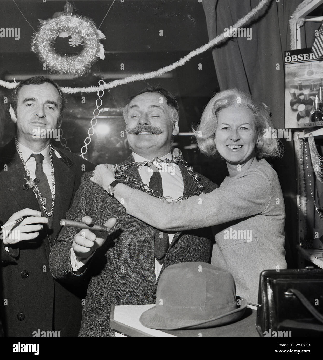 1960s, historical, comedy stars of the radio panel game, 'Does The Team Think' seen here at a party  with Jimmy Edwards, the creator the game on the right, smoking a large cigar, London, England, UK. Edwards was famous for his 'handlebar' moustache. The popular panel game, a parody of 'Any Questions' was played for laughs and ran for nearly twenty years. Stock Photo