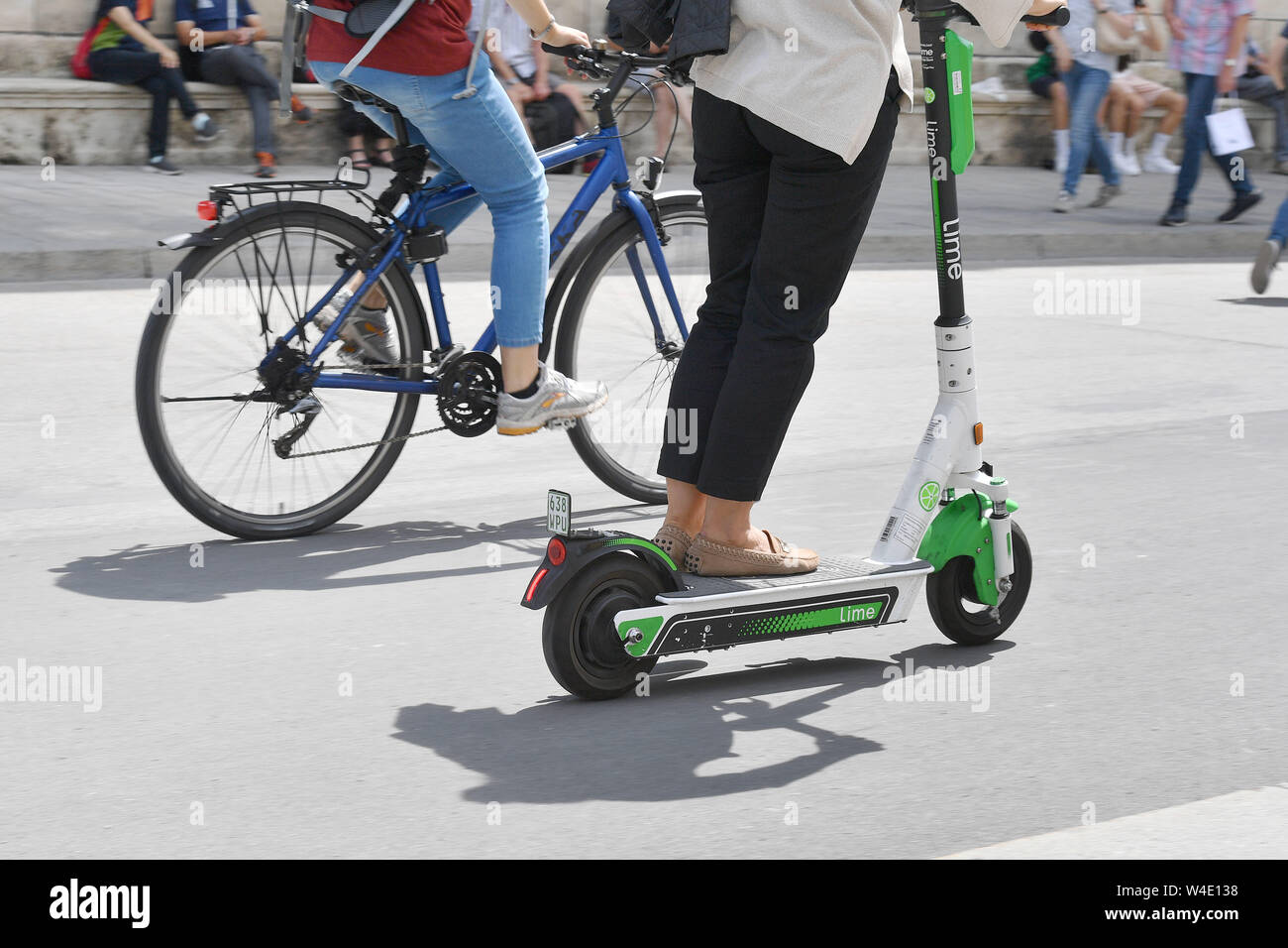 Munich, Deutschland. 22nd July, 2019. E-scooter competes on the road with a  bicycle, cyclist, rider. LimeBike, Lime Bike US e-scooter rental company.  E-scooter, e-scooter in the city center of Munich. Leihroller, Mietroller,