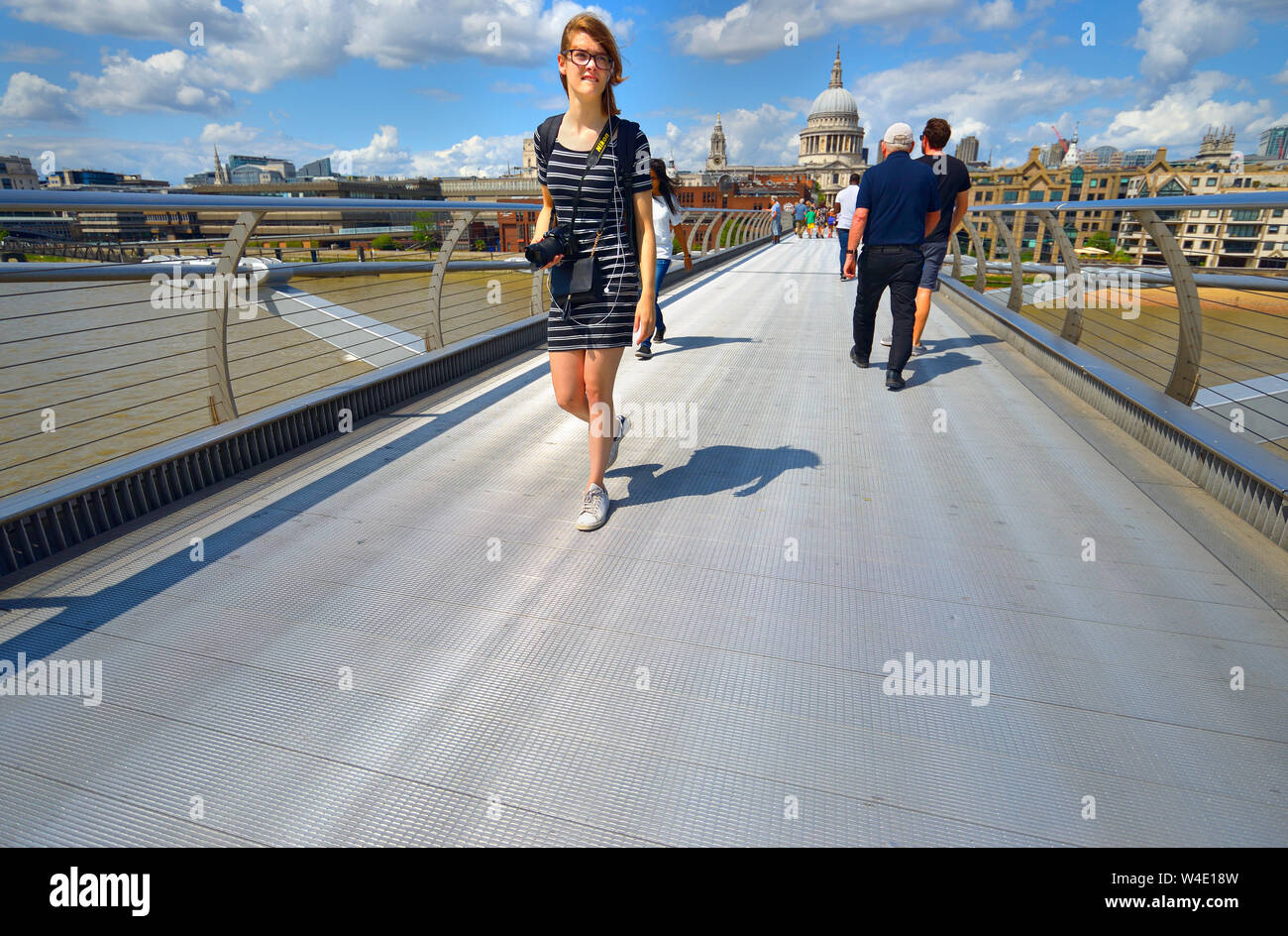 London, England, UK. Young woman crossing the Millennium Bridge Stock Photo