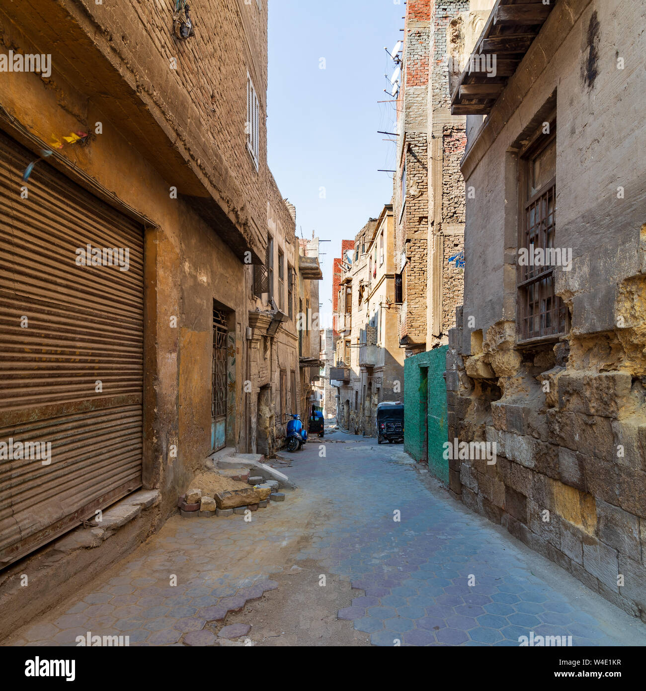 Aged houses with crumbling walls located on narrow abandoned street on sunny day in old Cairo, Egypt Stock Photo