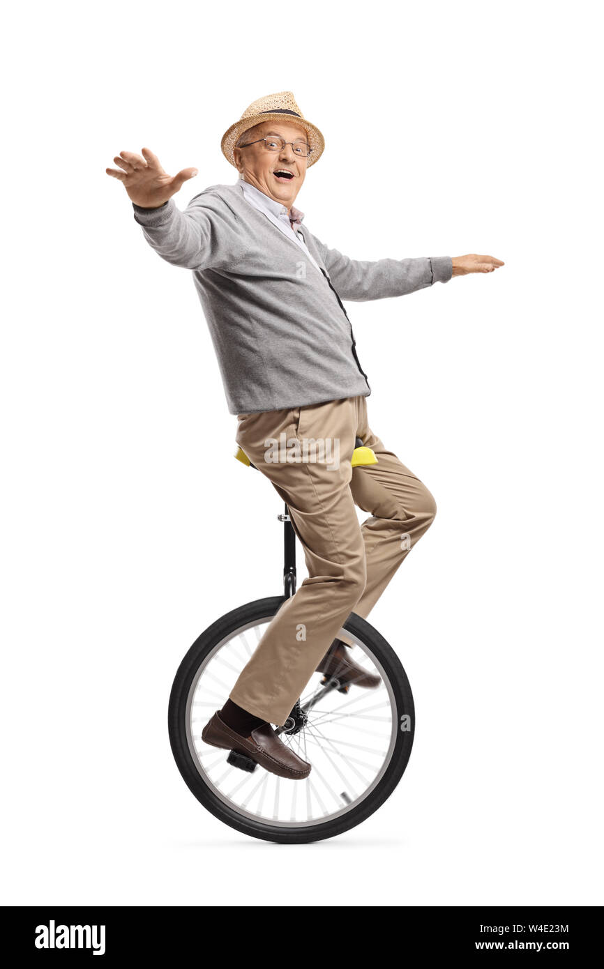 Full length shot of an excited elderly man riding a unicycle isolated on white background Stock Photo