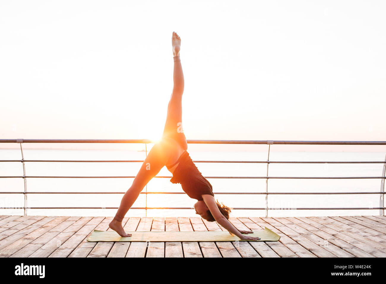 Woman doing yoga outside on the wooden floor. Stock Photo