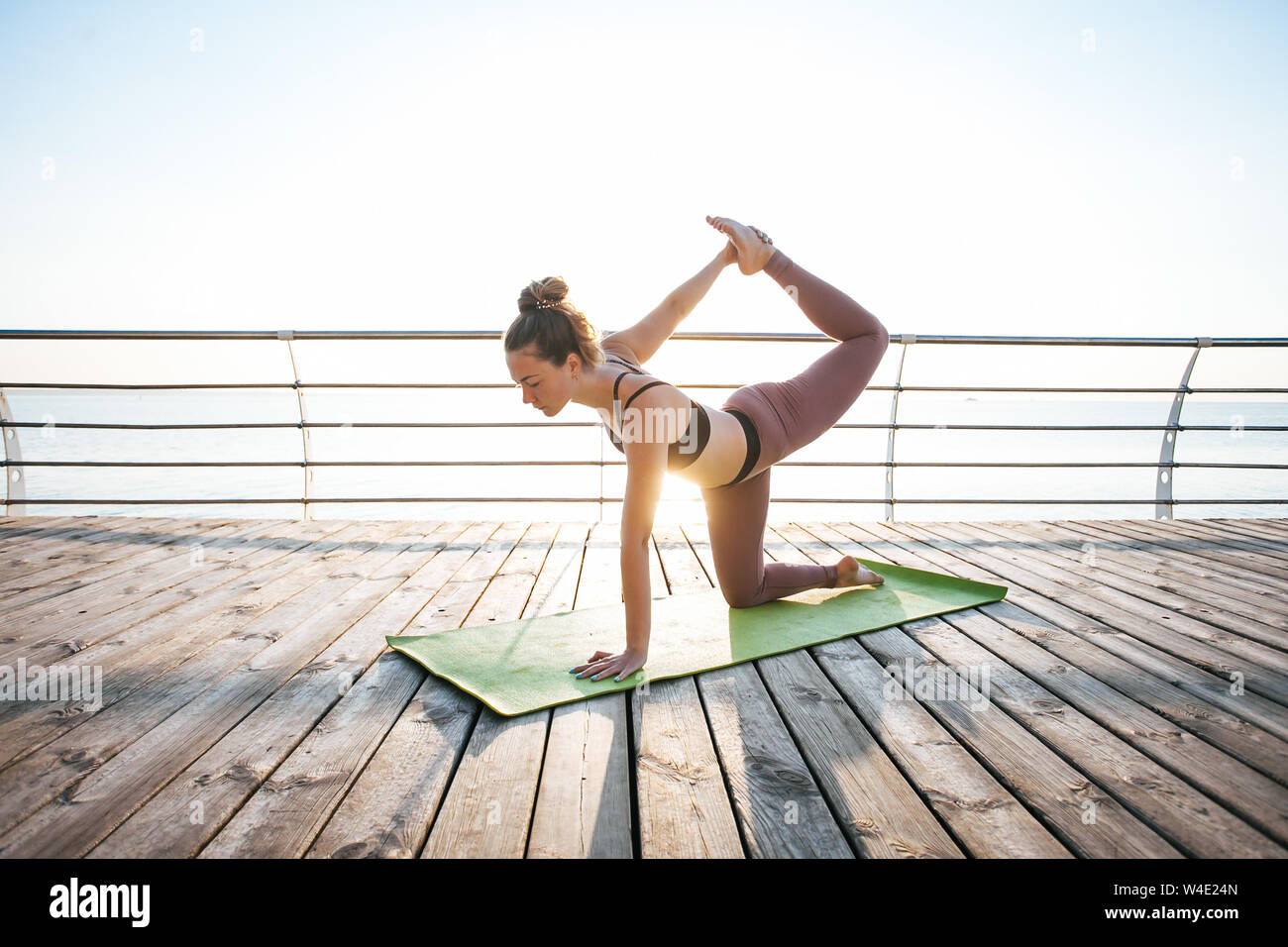 Woman doing yoga outside on the wooden floor. Stock Photo