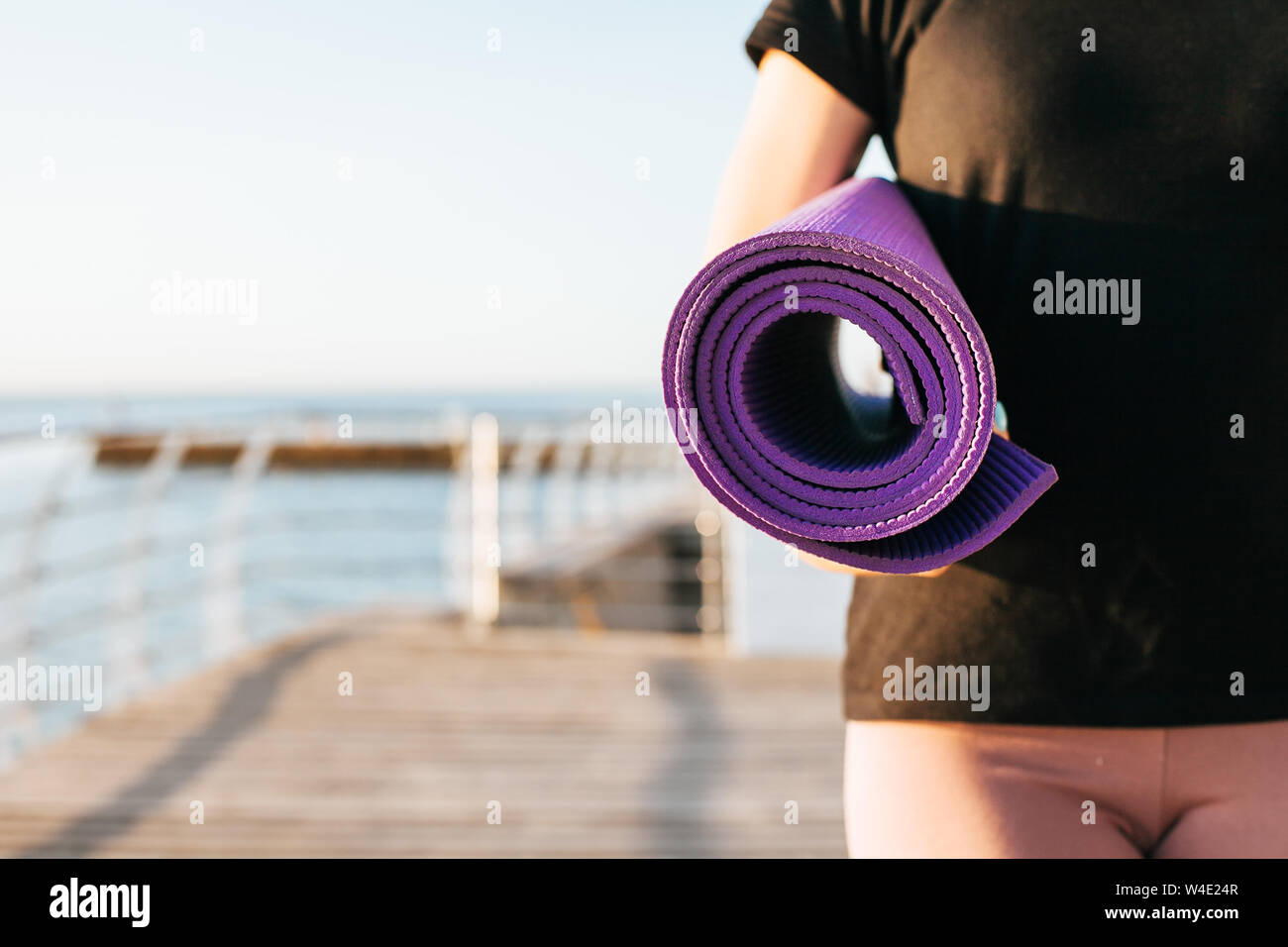 Close-up woman holding roll fitness or gray yoga mat after working out in the park Stock Photo