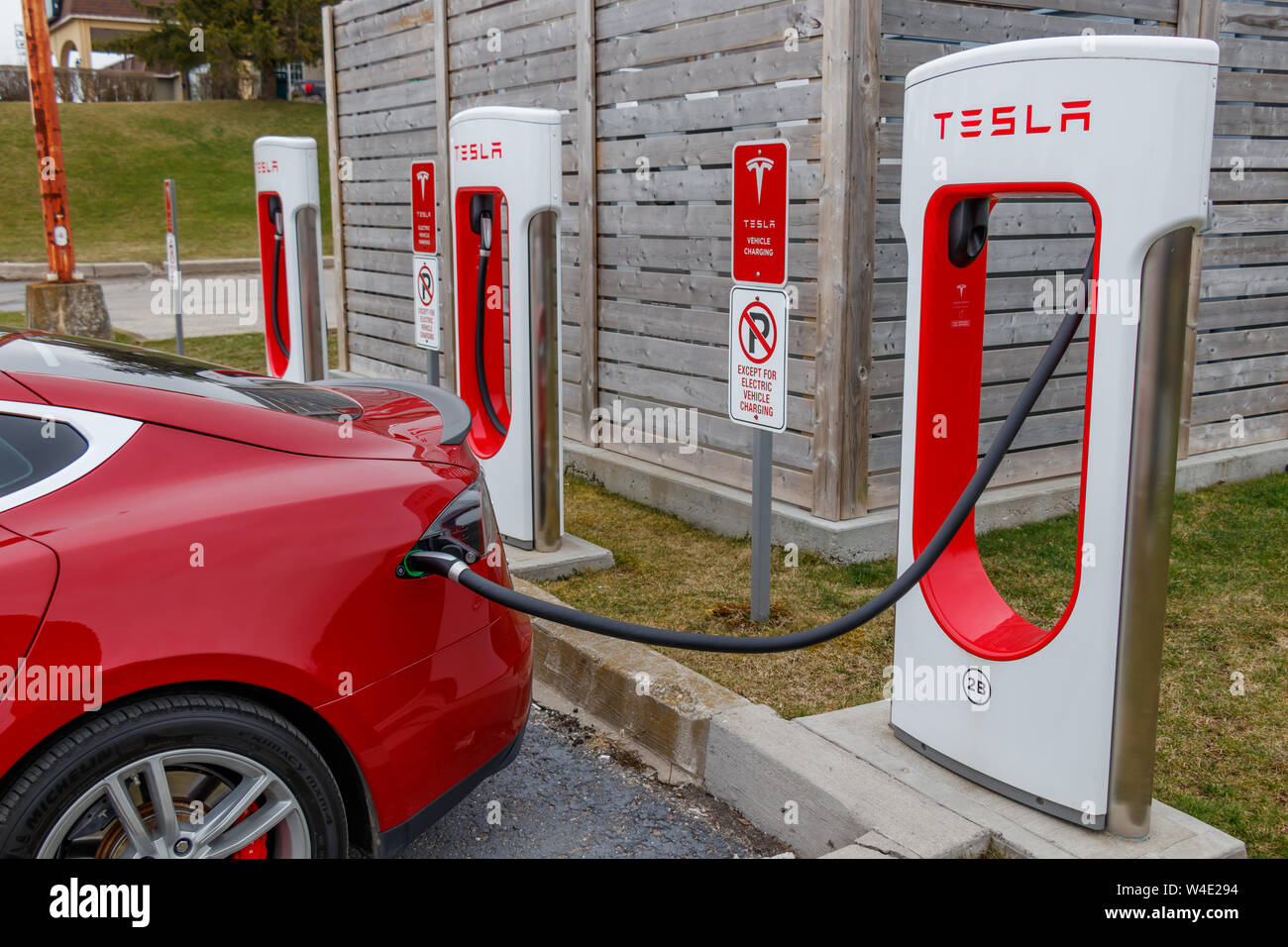 Closeup of Red Tesla Model S charging at Tesla Supercharger, Woodstock, Ontario. Stock Photo