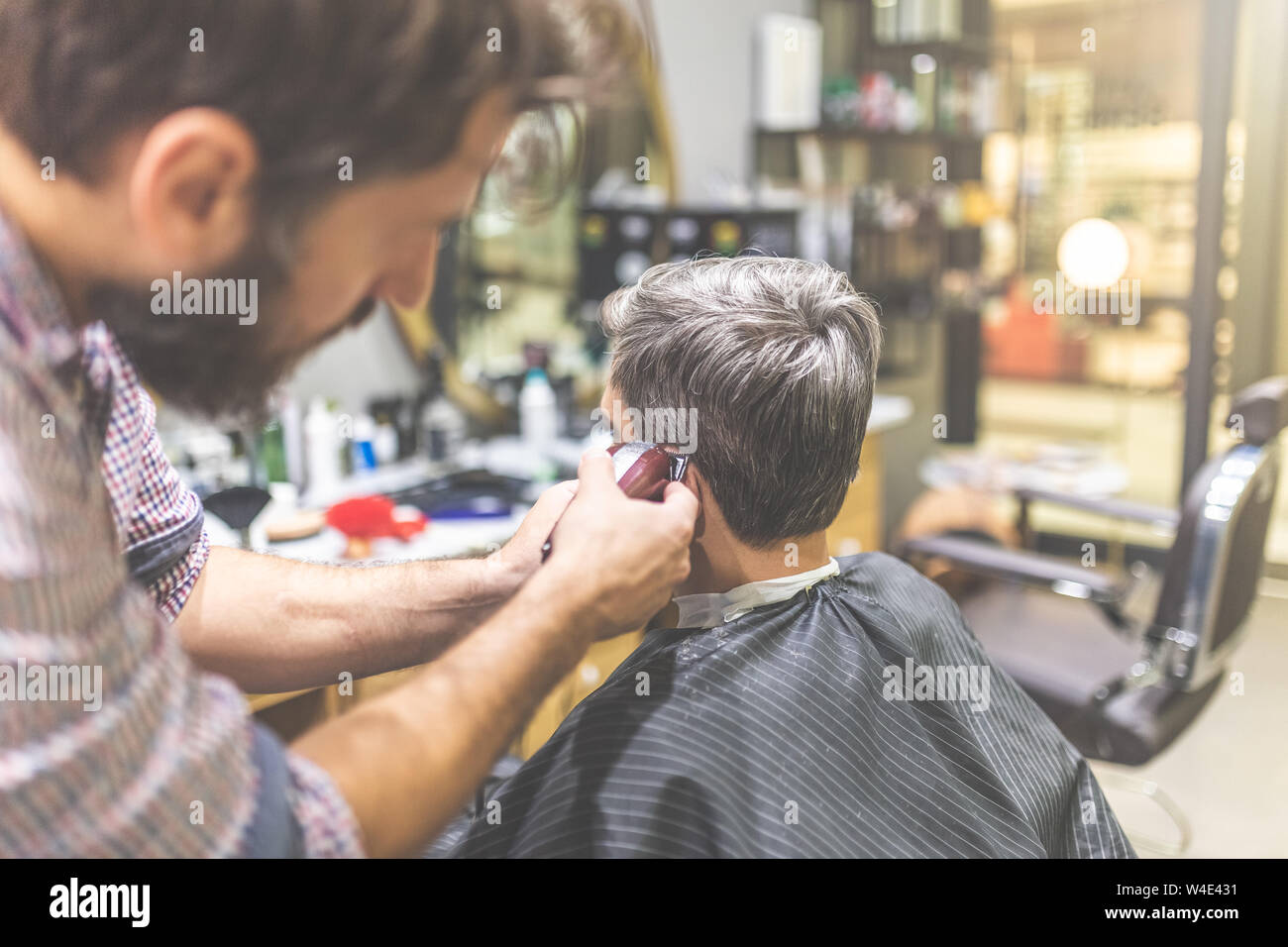 Barber styling hair of his client with clipper. Stock Photo