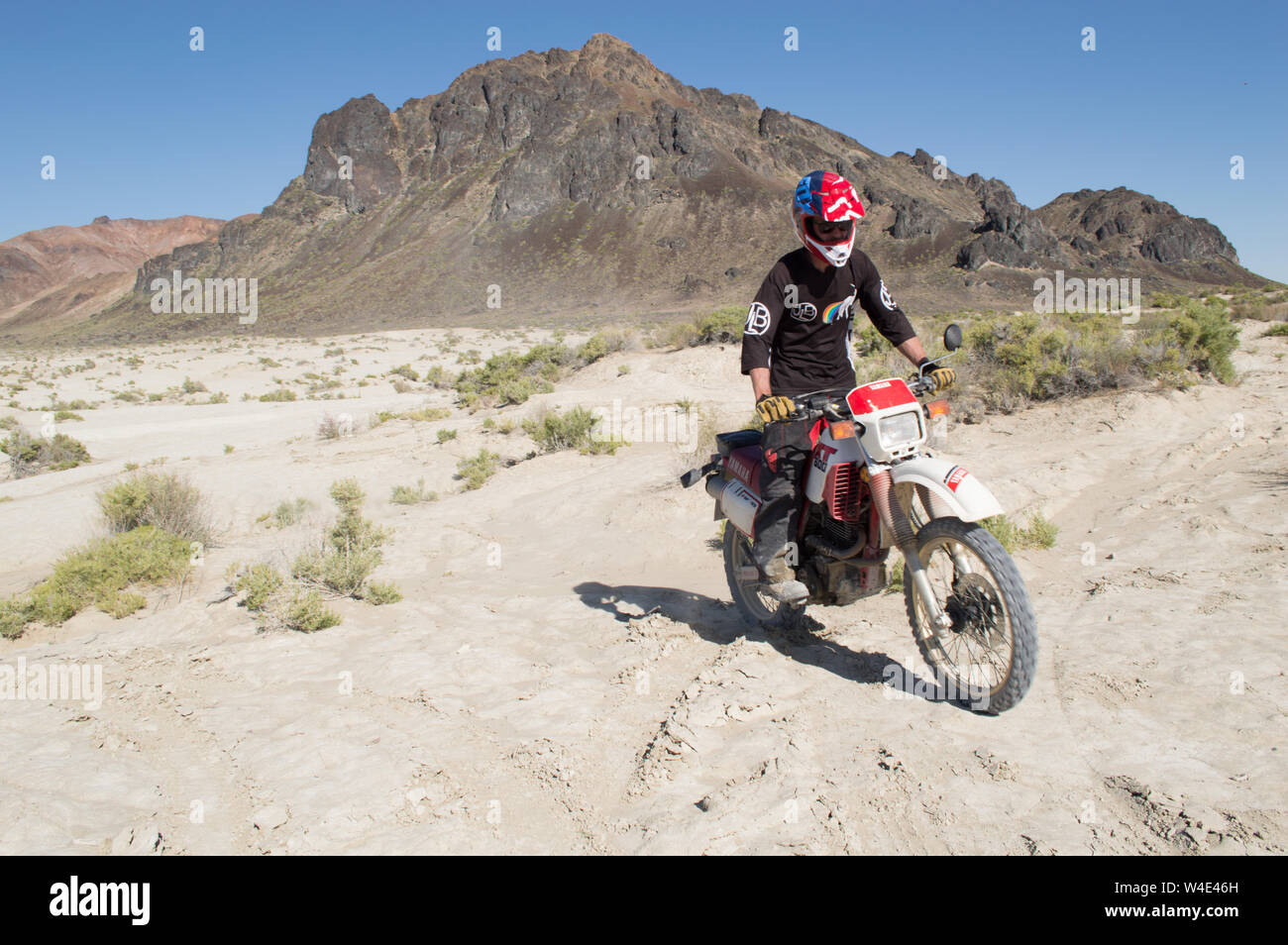 A young man rides a dirt bike through the Black Rock Desert on a sunny day. Stock Photo