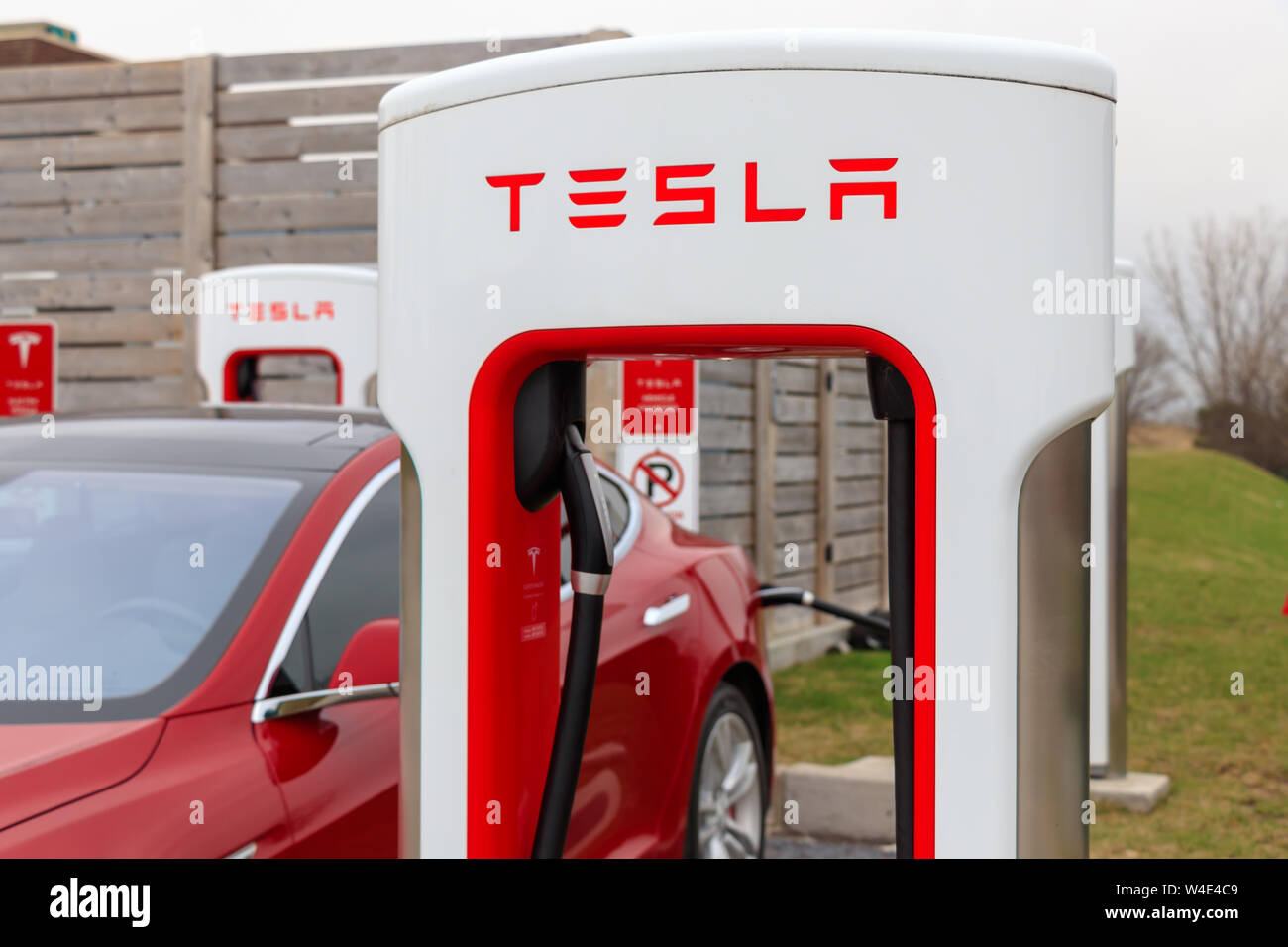 Tesla Supercharger Stall with Tesla Model S charging in background. Stock Photo