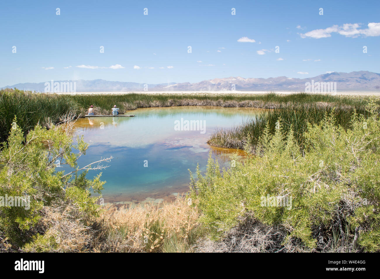 A couple sit on the dock by the the Black Rock Hot Spring near Gerlach, Nevada on a sunny day. Stock Photo