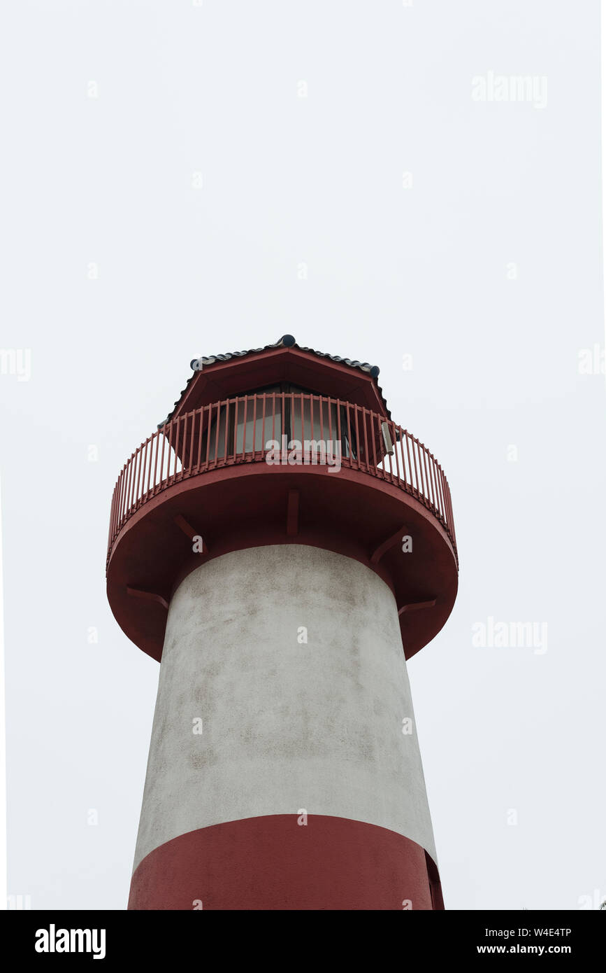 Looking up at red and white painted lighthouse with guard rails around top. Stock Photo