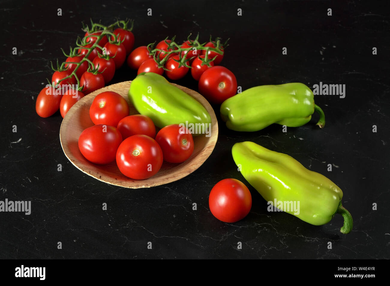 Tomatoes and green bell peppers on black board Stock Photo