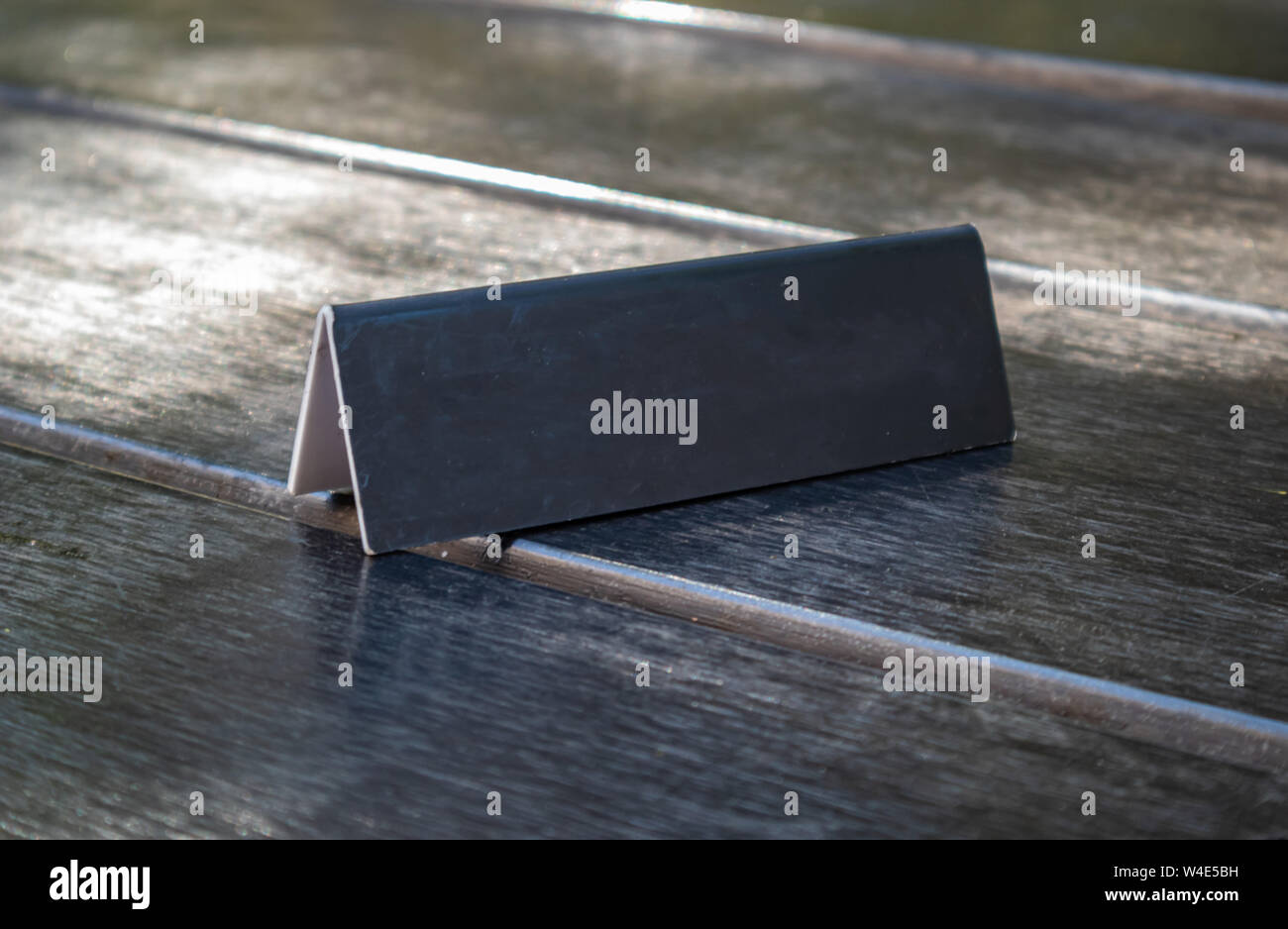Blank reserved sign, reservation concept. Metal black color plate mockup template on wooden table, copy space. Close up view with details Stock Photo
