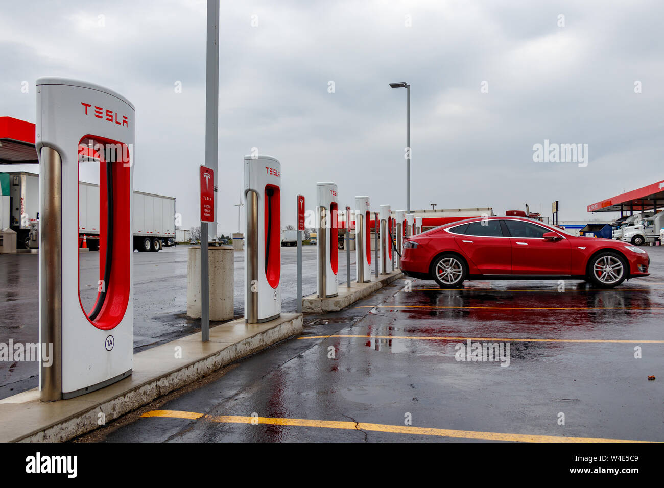 Tesla Supercharger Station with Tesla Model S charging in the rain. Stock Photo