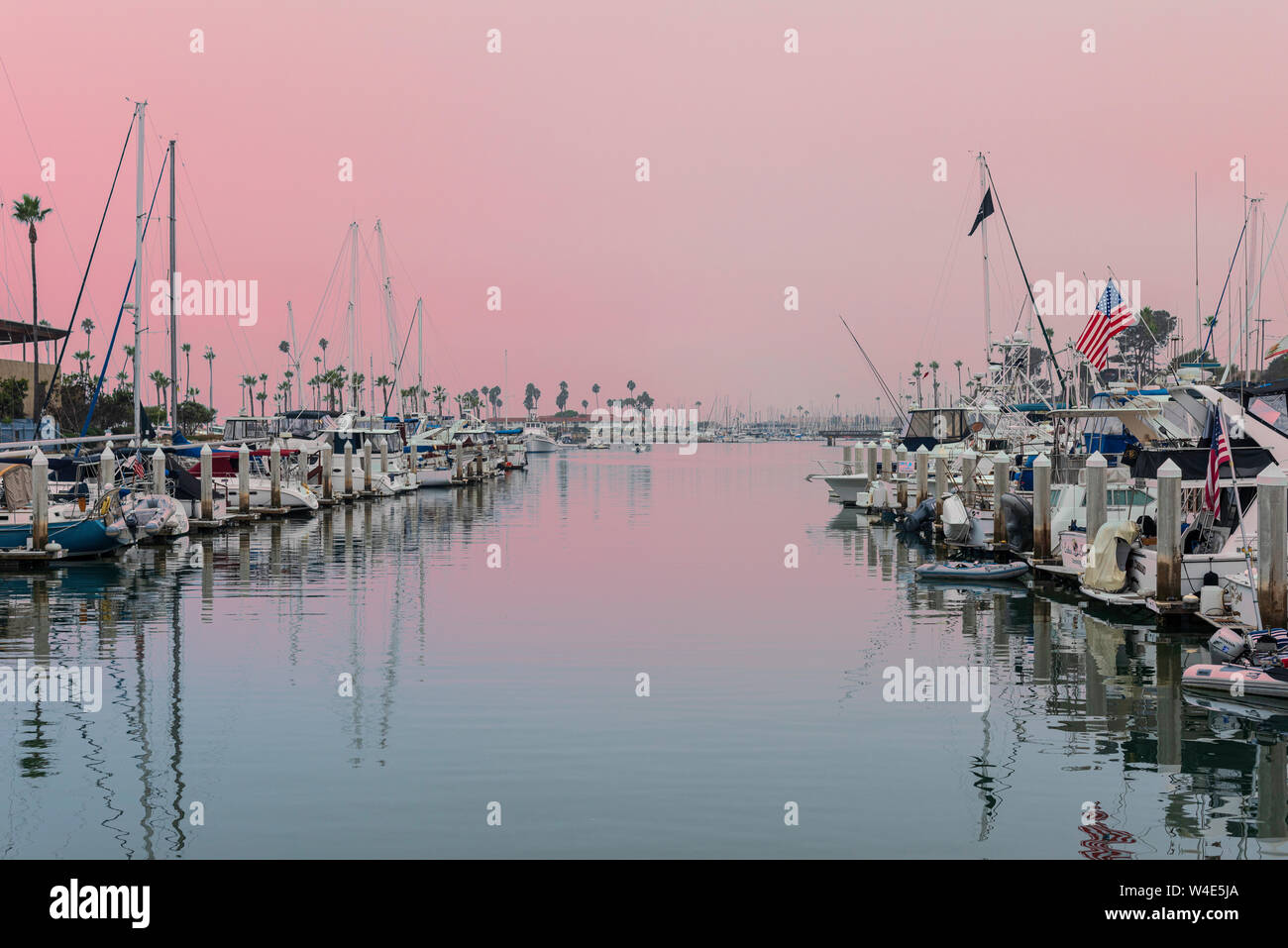 Pale pink sunset over harbor with boats docked. Stock Photo