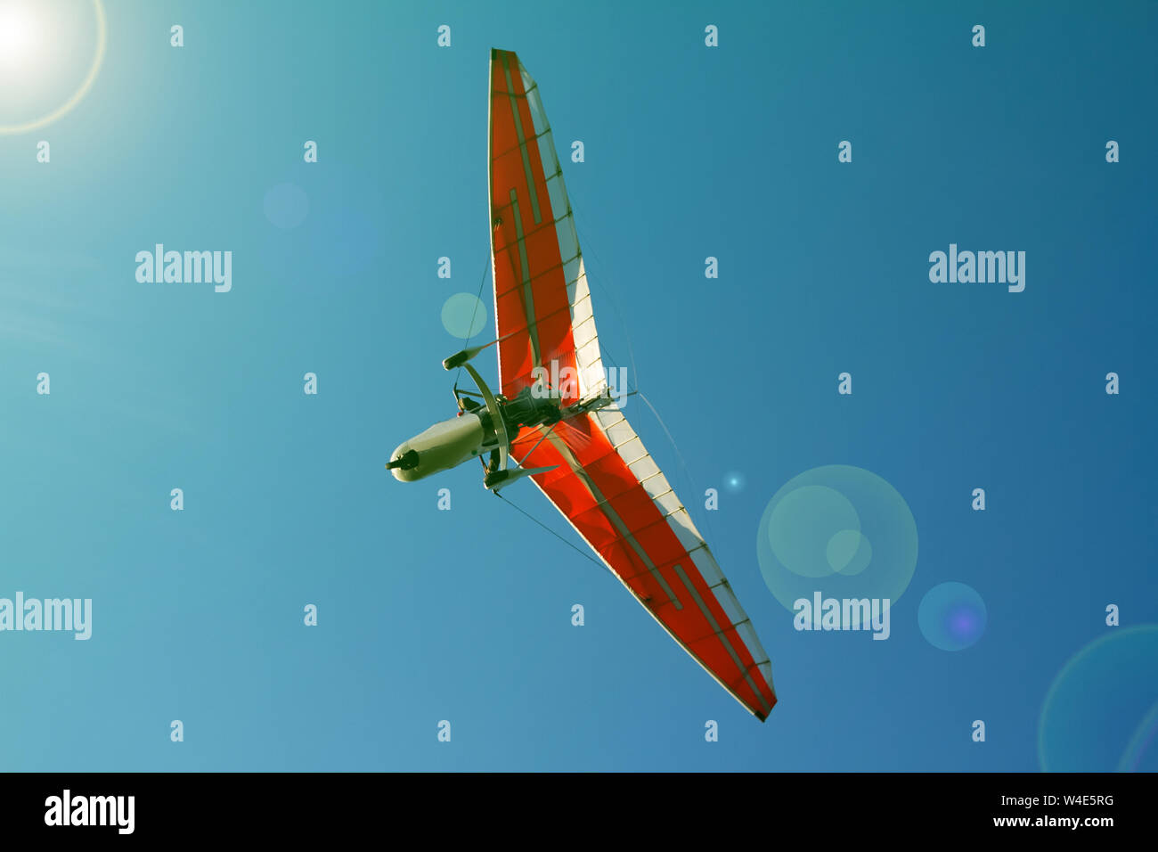 A bottom view super lightweight hang glider or trike flies in clear