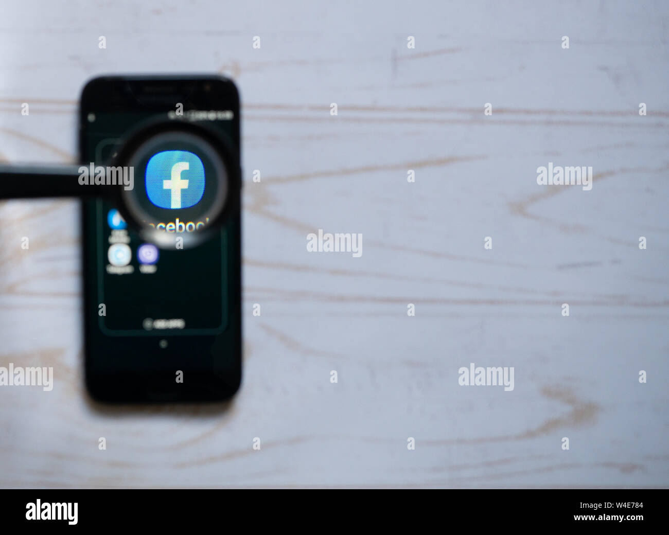 Nizhyn, Ukraine/ July-16-2019: Facebook app icon on the screen of modern smartphone menu, view through the looking glass. Social media, app, search co Stock Photo