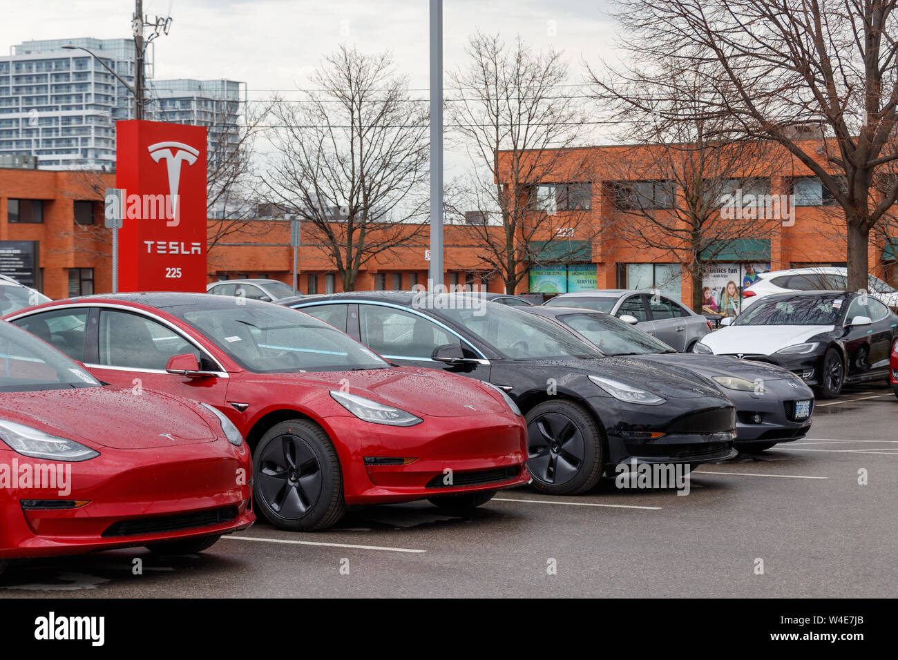 Tesla Model 3's at Tesla Dealership / Service Center in front of main gate sign. Stock Photo