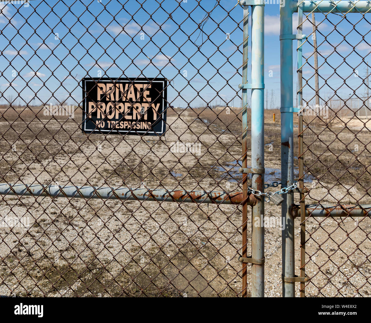 Chain link fence gates chained and locked with no trespassing, private property sign at the site of an abandoned and razed factory Stock Photo