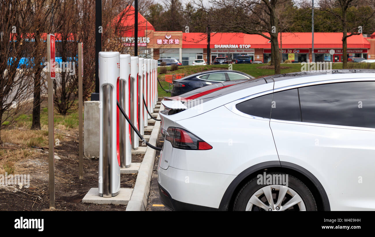 White Tesla Model X, Red and Blue Tesla Model all plugged in, supercharging at SmartCentres Markham Woodside, Tesla Supercharger. Stock Photo