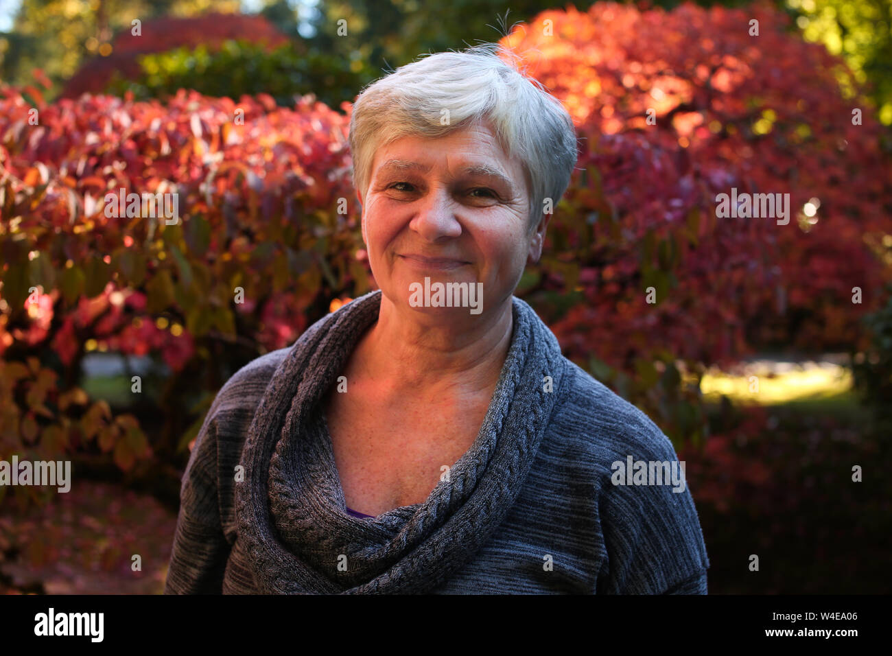 close up portraits of senior old women, bright red leaves background Stock Photo