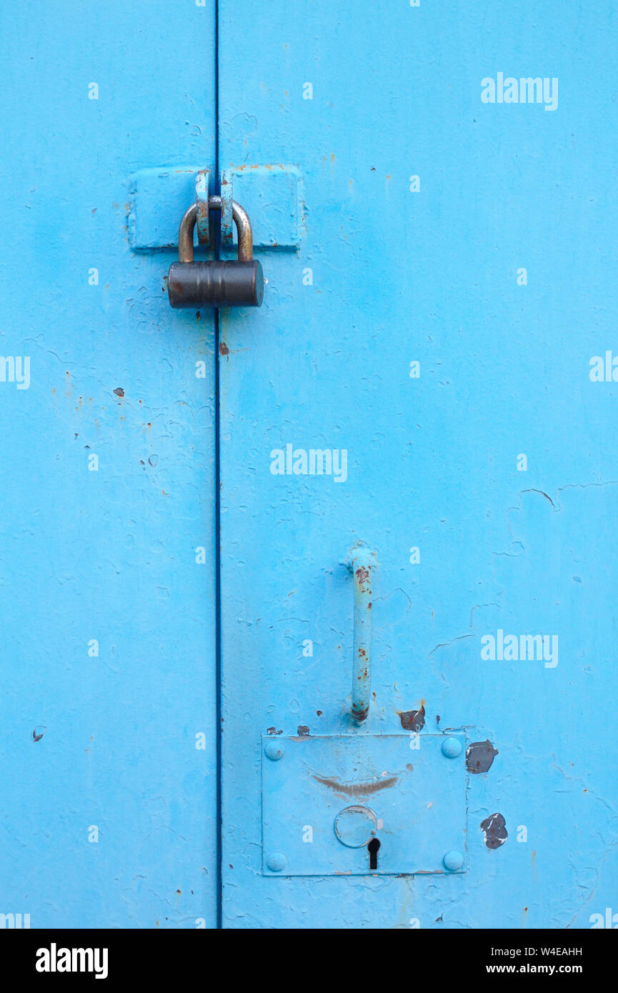 metal blue door with padlock. Old garage gates with keyhole Stock Photo