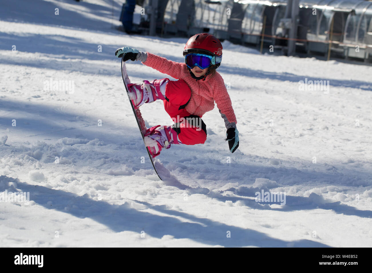 Little Cute Girl Snowboarding making a tricks at ski resort in sunny winter day. Caucasus Mountains. Mount Hood Meadows Oregon Stock Photo