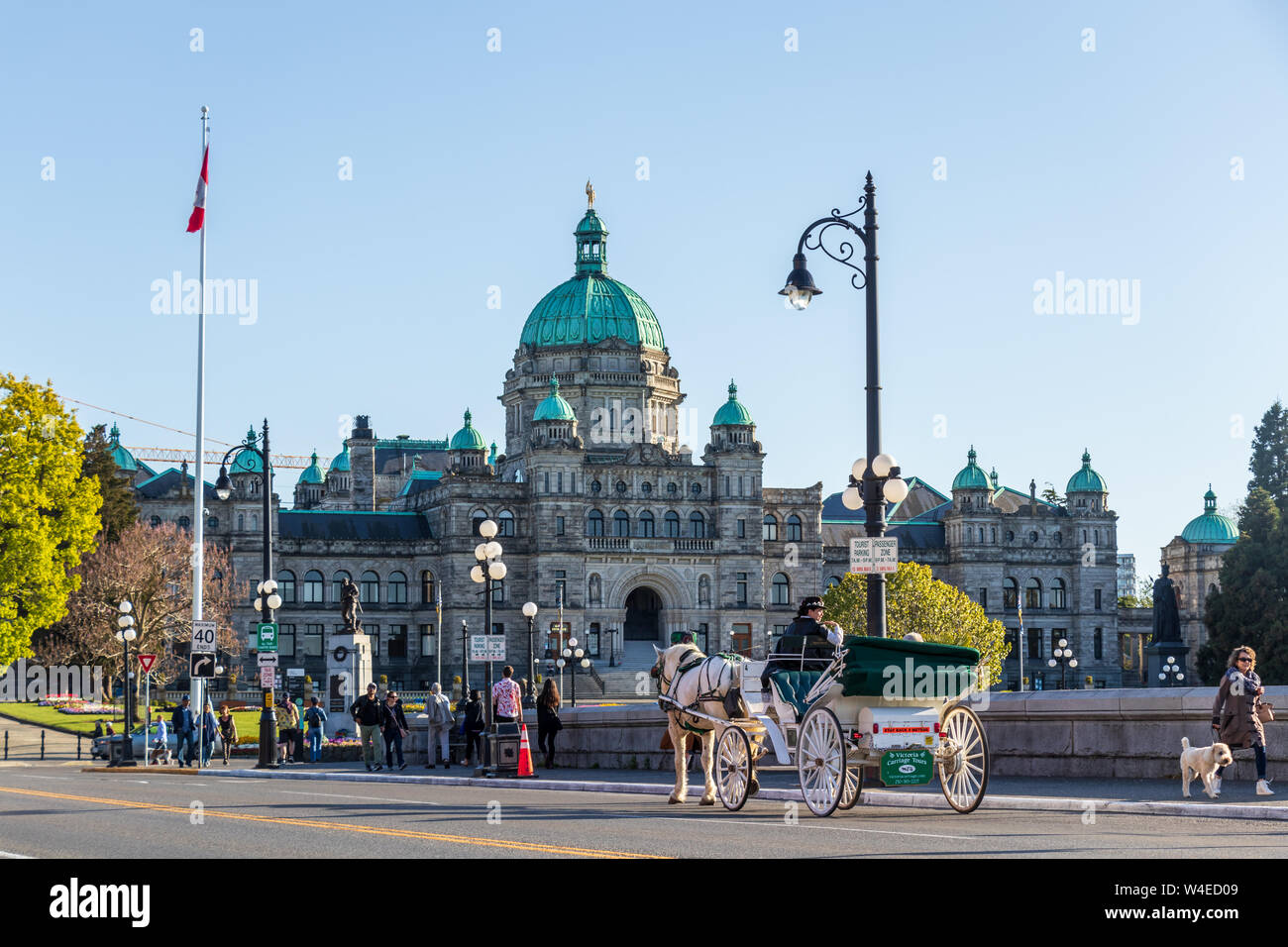 Legislative Assembly of British Columbia building seen while horse carriage travels in-front, along the Victoria, BC waterfront. Stock Photo