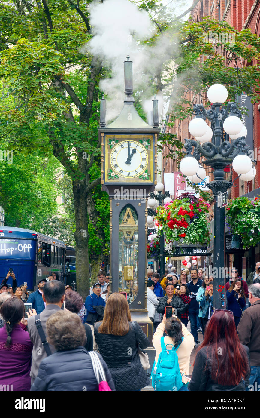 Street scene showing crowds watching the Gastown Steam Clock as it puffs steam at the top of the hour. Stock Photo