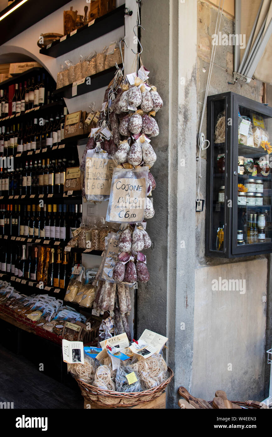 Wine shop in Cortana, Italy selling wine, olive oil, dried pasta, rice, jams, risotto and various meats and salami's that hang outside the store Stock Photo