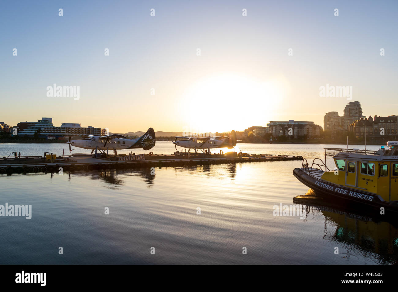Harbour Air seaplanes docked at port in downtown Victoria during a beautiful sunset over the harbour. Stock Photo
