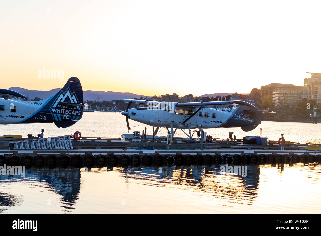 Harbour Air seaplanes docked at Victoria Harbour Airport during a beautiful sunset over the bay. Stock Photo